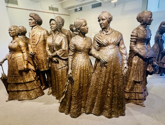 Life-size bronze statues of the “First Wave” of activists stand like sentinels in the foyer of the Visitors Center of the Women's Rights Park.